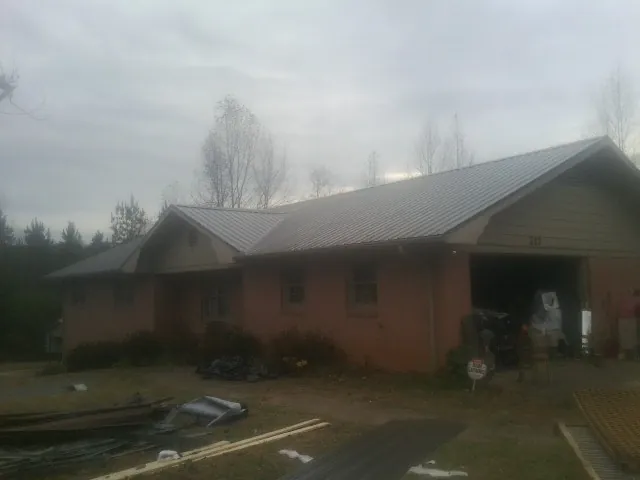Gray metal roof on a stucco house with an attached garage in Weldon