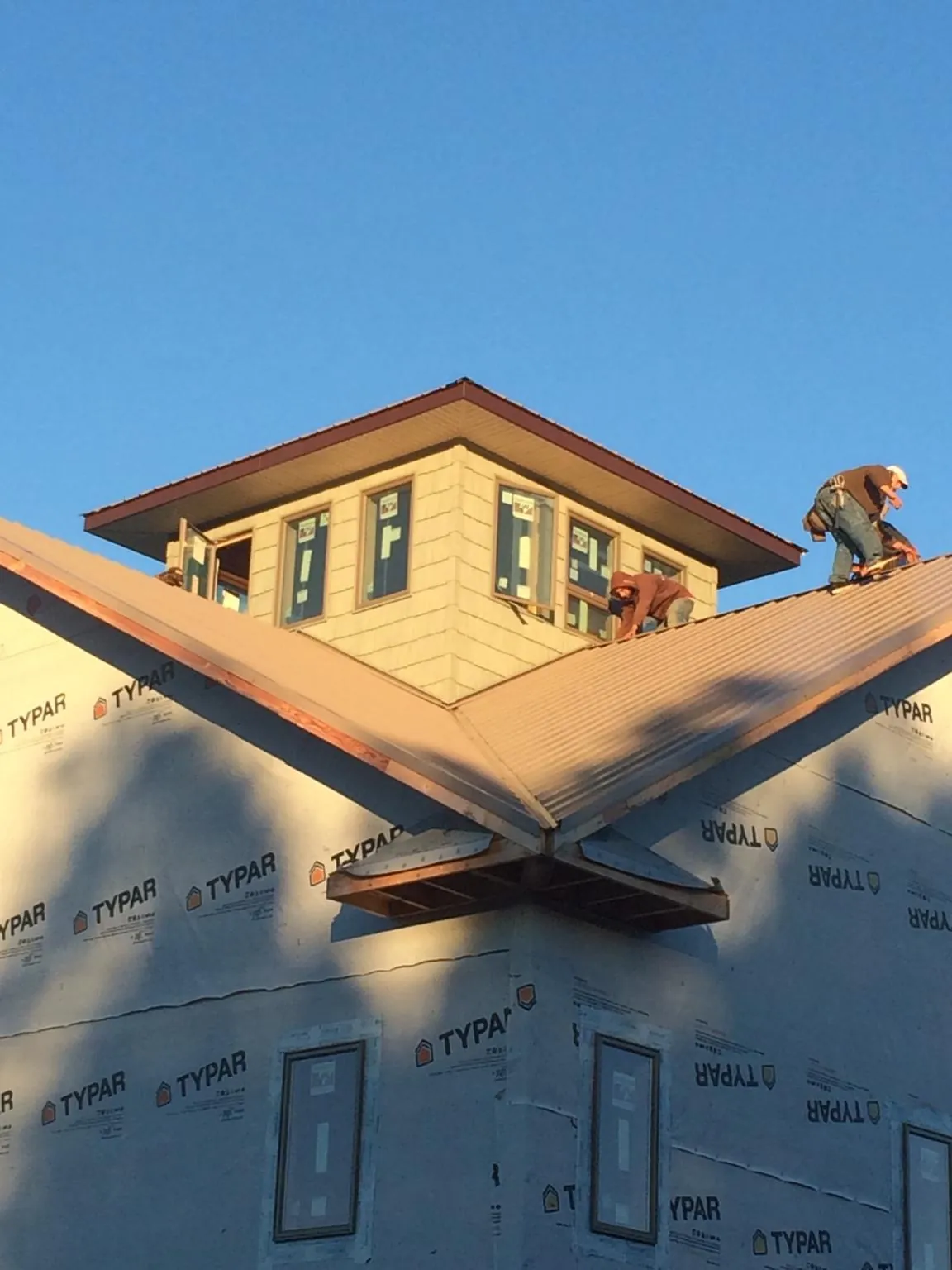 Roofers working around a rooftop cupola on a new metal roof at sunset — Roof Waterproofing in Weldon by Roofing Brothers
